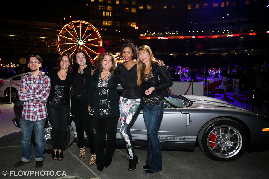 guests posing in front of a sports car