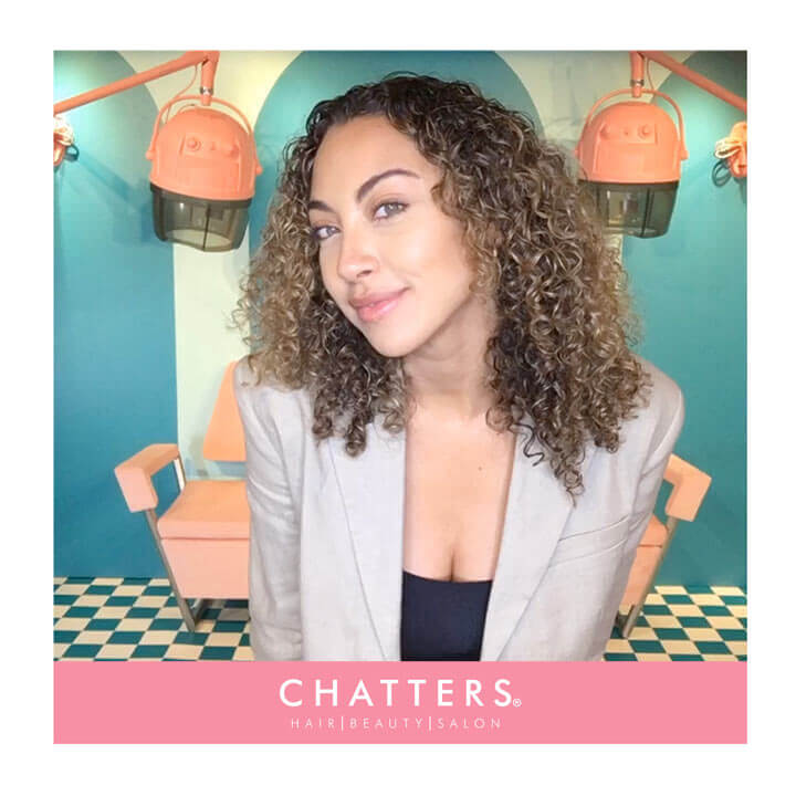 A woman with curly hair posing in a video photo booth