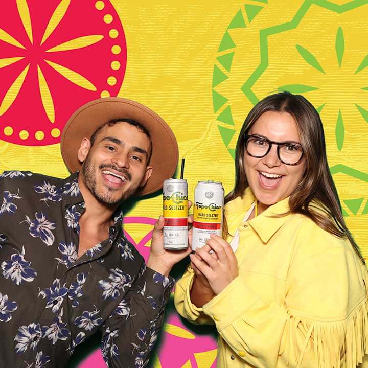 A man and a woman posing with Topo Chico drinks at a patio launch