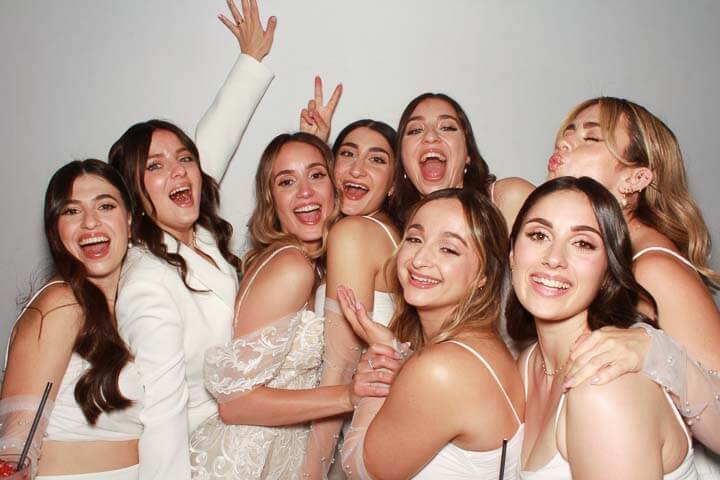 a bride and her bridesmaids having fun in the photobooth