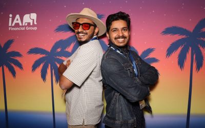 Two men posing in front of a custom printed backdrop with palm trees