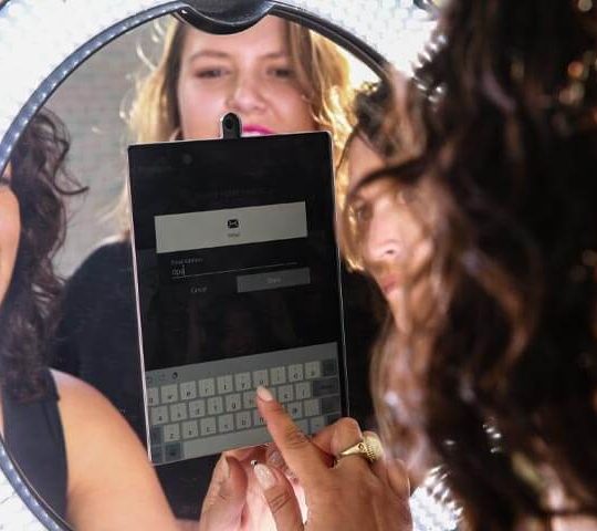 Share A lady inputting her email address into a photo booth so that she can share her photo to social media