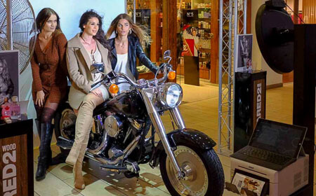 three ladies posing on a harley davidson motor bike at a retail store photo booth