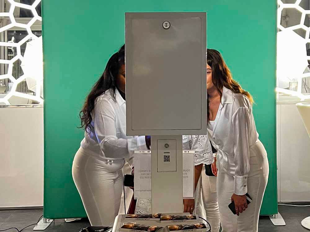 three ladies interacting with a photo booth with a green screen