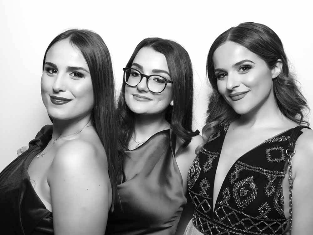 A black and white photo of Three ladies posing on a white background in the Snapshot Photobooth Hollywood Glam Photo Booth