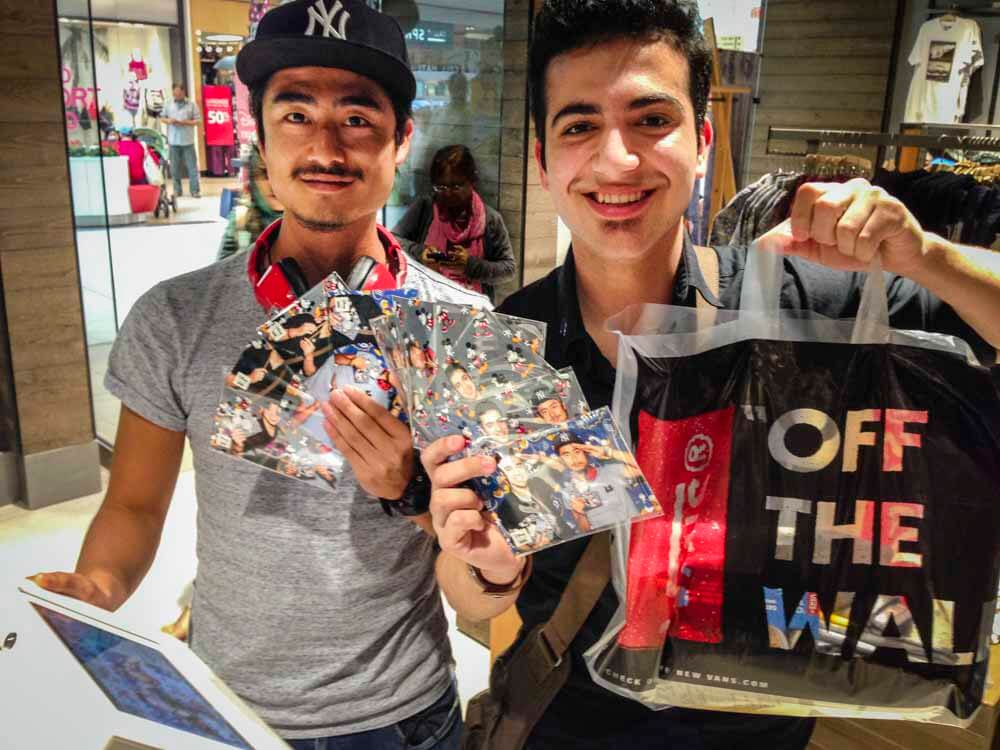 two young men showing their photo booth photos inside a Vans sneaker store