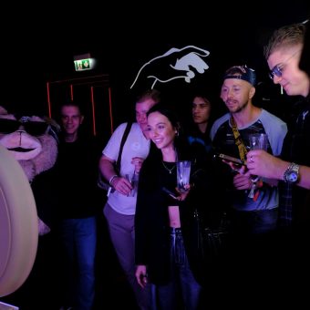 Corporate Event Photo Booth Engagement Group of people gathered around a photo booth, taking fun pictures during a company event activation