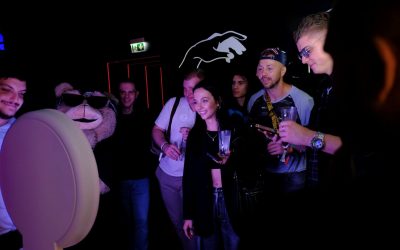 Group of people gathered around a photo booth, taking fun pictures during a company event activation